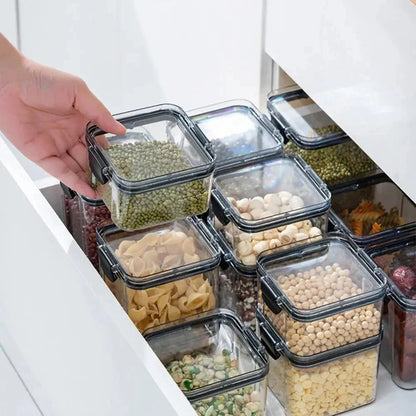 Hand organizing clear food storage containers with grains, pasta, beans in a kitchen drawer