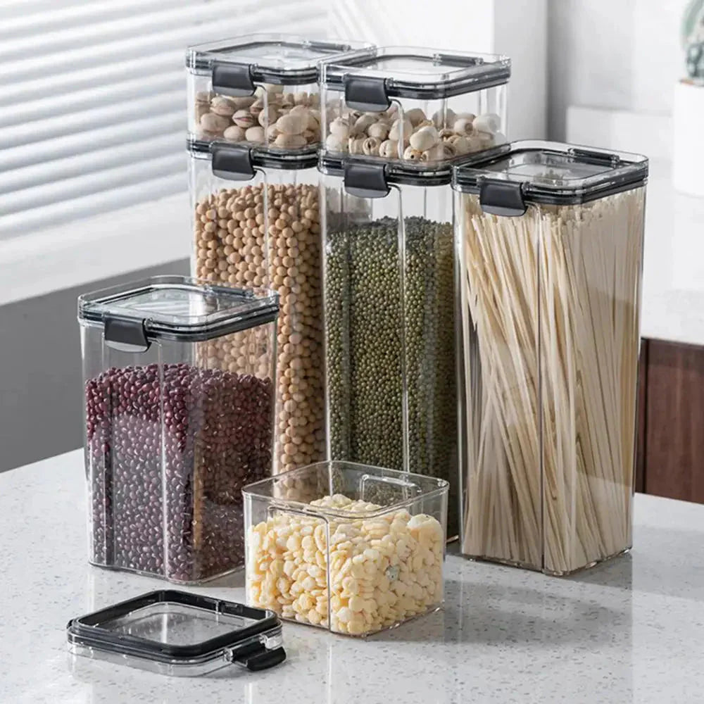 Clear kitchen storage containers with airtight lids holding pasta, beans, and snacks on countertop