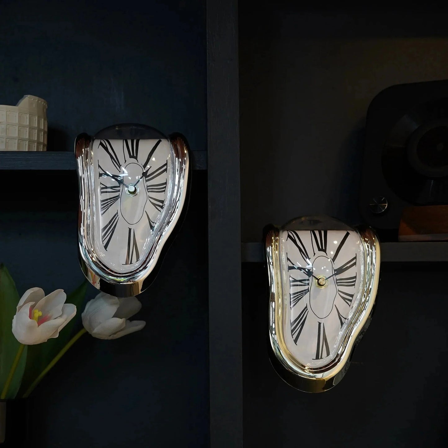 Two melting wall clocks with Roman numerals on a dark shelf, surreal home decor