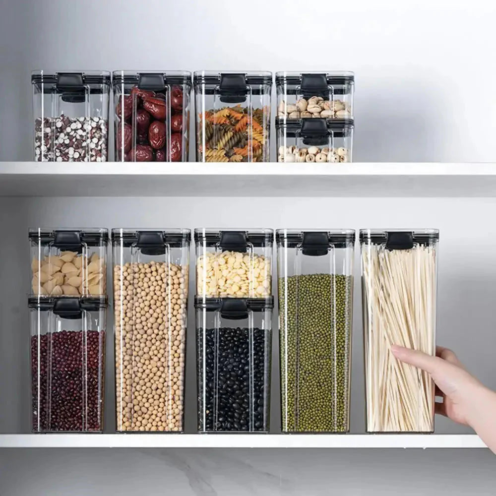 Clear kitchen storage containers on shelves, organized with beans, pasta, and dried foods.