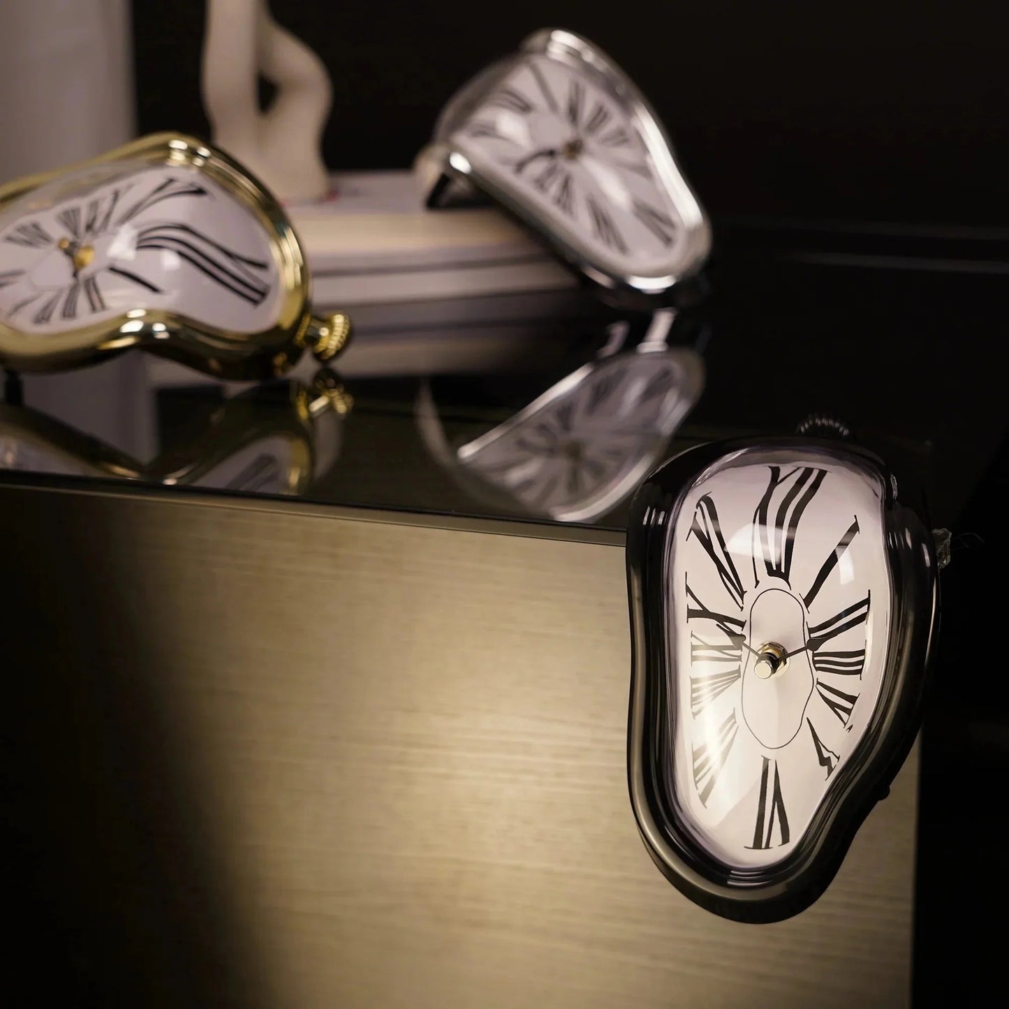 Surreal melting desk clocks with Roman numerals in gold, silver, and black finishes