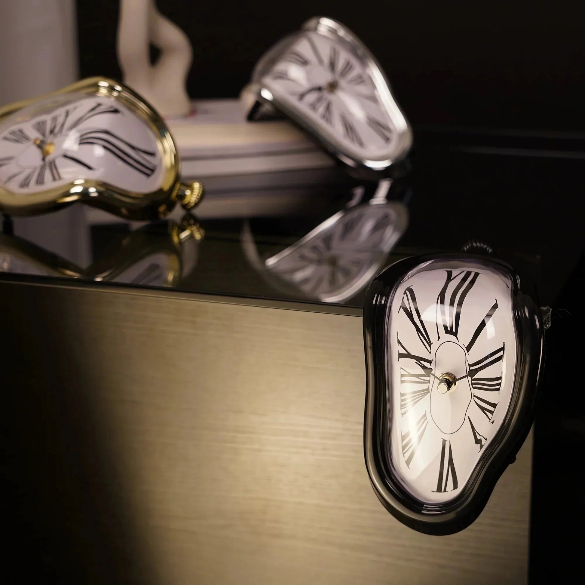 Surreal melting desk clocks with Roman numerals in gold, silver, and black finishes